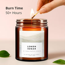 Load image into Gallery viewer, Candle labeled 'Lemon Sugar' being lit with a match, on a light background.
